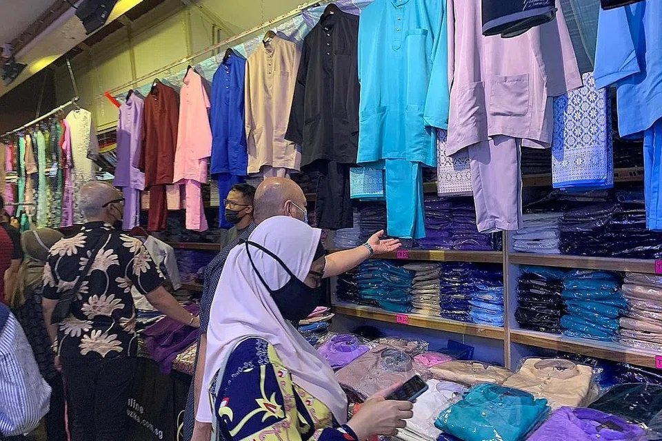 GAYA APA TAHUN INI?: Beberapa pengunjung ke Joo Chiat Complex dilihat membelek-belek baju Melayu yang digantung, sesuai dijadikan pakaian Hari Raya. - Foto BH oleh ZULAIQAH ABDUL RAHIM 