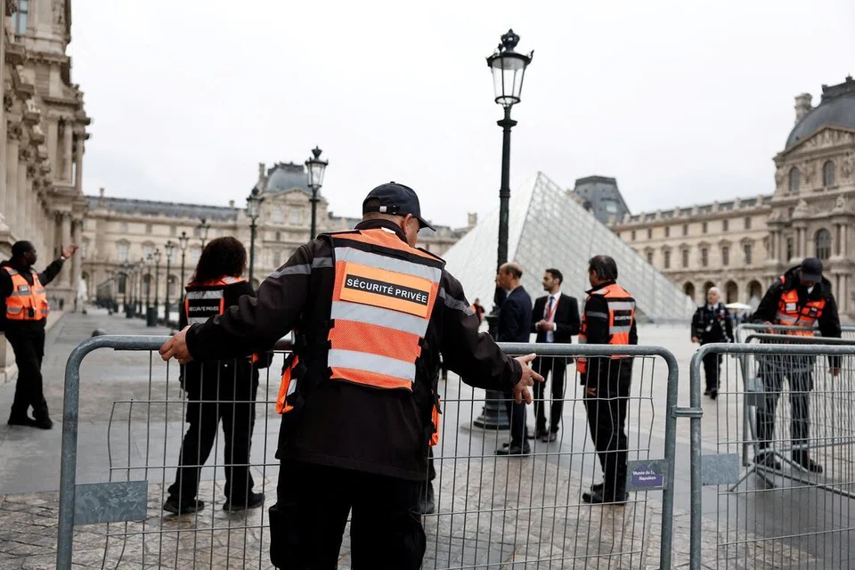 Petugas keselamatan memasang pengadang berhampiran Piramid kaca Muzium Louvre ketika muzium itu kekal ditutup sehari selepas rompakan permata yang dramatik di Paris, Perancis, pada 20 Oktober. 
