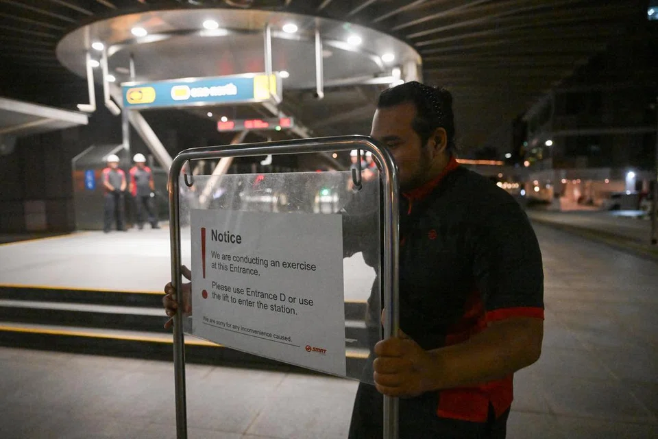 Seorang kakitangan SMRT memasang papan tanda untuk memaklumkan orang ramai tentang latihan simulasi yang dijalankan di Stesen MRT One-North pada 12 Disember.