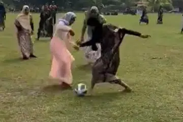 REBUT BOLA: Sekumpulan lelaki di daerah Felda Lepar Hilir Lama, Pahang, mengenakan seragam baju kelawar dan batik semasa bermain bola.