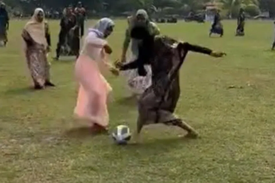 REBUT BOLA: Sekumpulan lelaki di daerah Felda Lepar Hilir Lama, Pahang, mengenakan seragam baju kelawar dan batik semasa bermain bola.