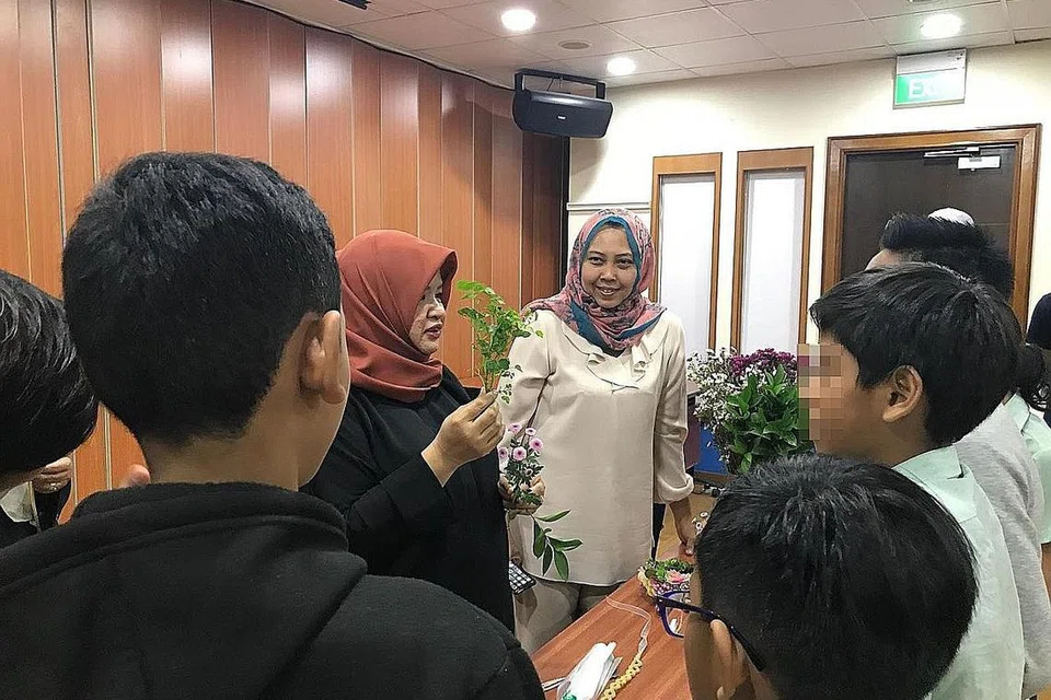 BELAJAR GUBAH BUNGA: Cik Hamidah (berbaju hitam) mengajar kanak-kanak cara membuat gubahan bunga sewaktu sesi itu. Menerusi bengkel khas itu, Cik Haslinda (tengah) berharap mereka dapat membawa pulang kemahiran baru yang mungkin dapat digunakan pada masa depan. - Foto DANA PENDIDIKAN HARUN GHANI