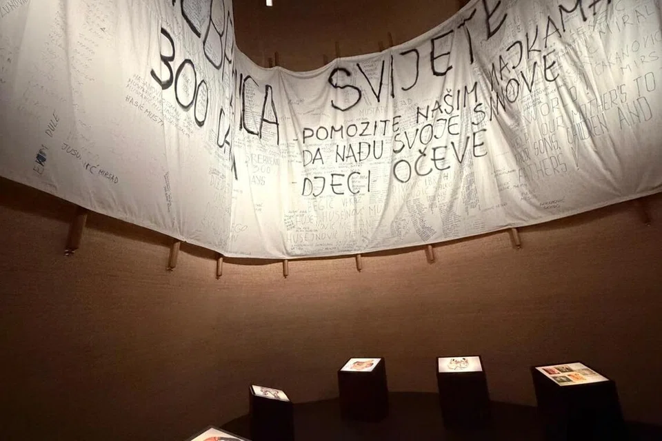 Kain dengan tulisan yang dihasilkan oleh wanita Persatuan Srebrenica, Bosnia-Herzegovina, 1996 yang dipamerkan di dalam ICRC Geneva. 