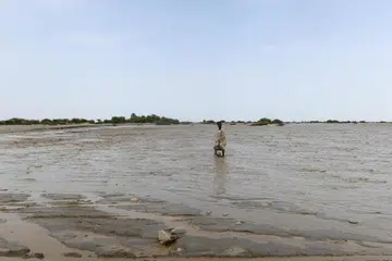 Seorang penduduk dilihat mengharungi banjir yang melanda di Pelabuhan Sudan pada 26 Ogos.