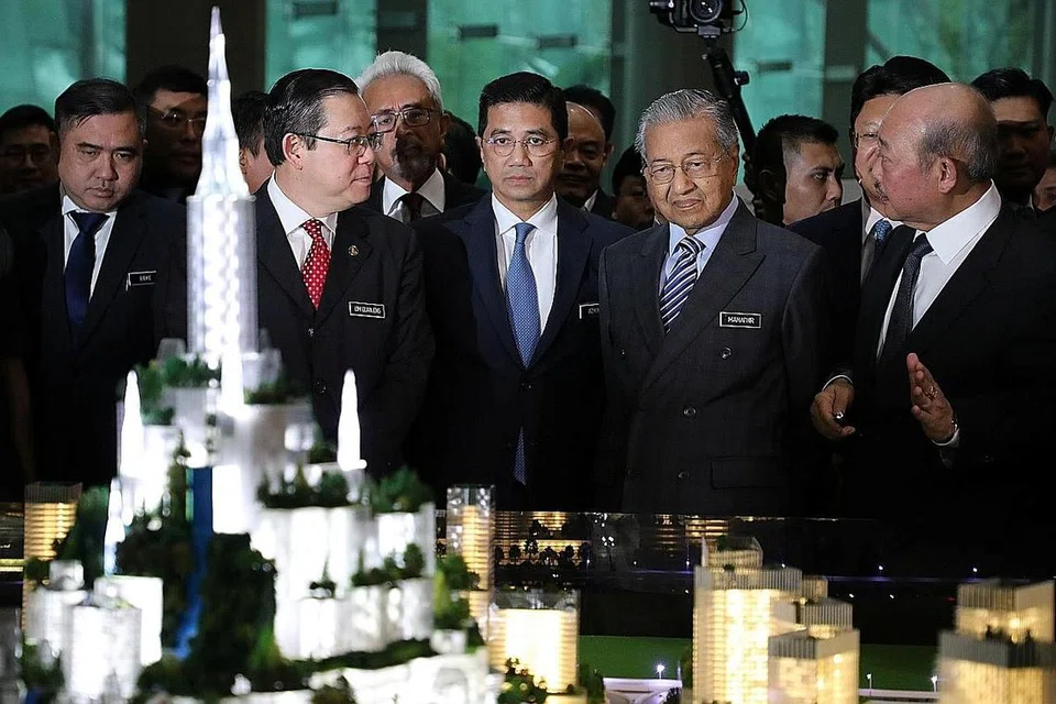 BOLEH JANA MANFAAT EKONOMI: Dr Mahathir (dua dari kanan) bersama (dari kiri) Menteri Pengangkutan Anthony Loke Siew Fook, Menteri Kewangan Lim Guan Eng dan Menteri Hal Ehwal Ekonomi Azmin Ali, melihat model Bandar Malaysia sebelum majlis menandatangani perjanjian di Putrajaya kelmarin. - Foto REUTERS
