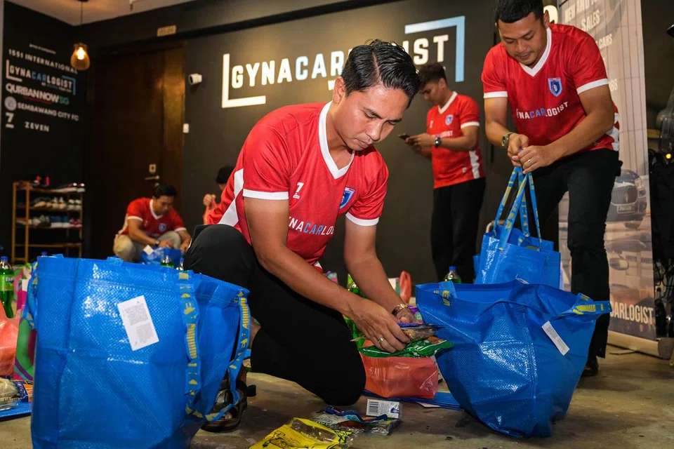 Bekas kapten pasukan bola sepak Singapura, Shahril Ishak (depan), bersama beberapa lagi bekas pemain kebangsaan menyiapkan habuan Hari Raya untuk diagih kepada penduduk Jalan Kukoh pada 22 Mac. 