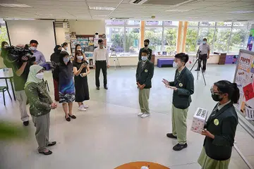 AMALAN SIBER SELAMAT: (Dari kanan) Pelajar menengah tiga Sekolah Menengah Pasir Ris, Nur Marsya Aqisyah Mazalan, Ryan Qiu, dan Davwin Arinze Akanihu, menerangkan mengenai Program Kesejahteraan Siber - yang mendidik pelajar mengenal pasti berita palsu, mengamalkan sikap bertanggungjwab di Internet, keselamatan siber dan pembulian siber - kepada Presiden Halimah Yacob. - Foto BH oleh KEVIN LIM