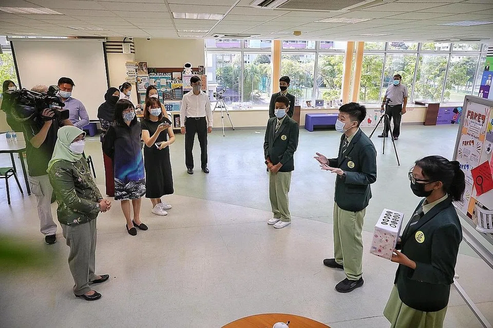 AMALAN SIBER SELAMAT: (Dari kanan) Pelajar menengah tiga Sekolah Menengah Pasir Ris, Nur Marsya Aqisyah Mazalan, Ryan Qiu, dan Davwin Arinze Akanihu, menerangkan mengenai Program Kesejahteraan Siber - yang mendidik pelajar mengenal pasti berita palsu, mengamalkan sikap bertanggungjwab di Internet, keselamatan siber dan pembulian siber - kepada Presiden Halimah Yacob. - Foto BH oleh KEVIN LIM