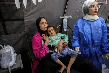 Seorang wanita Palestin bersama kanak-kanak yang cedera dalam serangan Israel, di sebuah hospital ketika tentera Israel melancarkan operasi darat dan udara di bahagian timur Rafah.