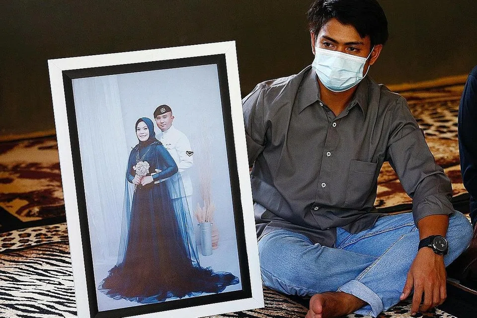 SATU KEHILANGAN: Encik Imam Yoga, 26 tahun, yang merupakan abang ipar Encik Pandu Yudha Kusuma, 23 tahun, salah seorang anak kapal yang terkorban dalam tragedi KRI Nanggala-402, menunjukkan sebuah potret mangsa dan isteri di rumah orang tua mereka di Banyuwangi. - Foto REUTERS
