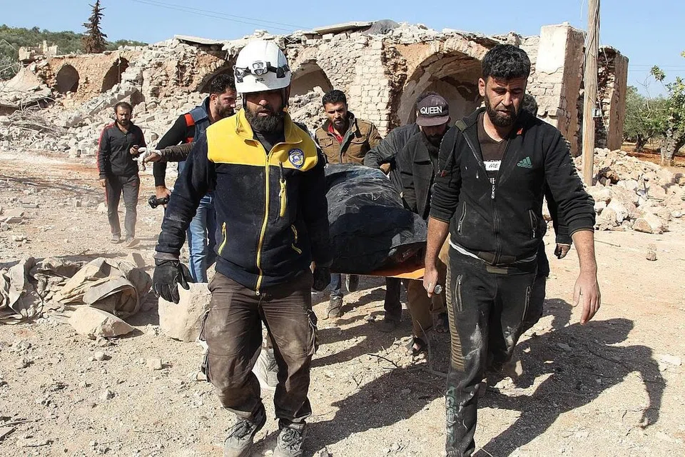 GOTONG-ROYONG BANTU MANGSA: Anggota pertahanan awam Syria yang dikenali juga dengan gelaran 'Topi Keledar Putih' mencari mangsa serangan udara dan kemudian membawa mayat mereka ke tempat yang disiapkan khas. Serangan itu berlaku di sebuah kampung, Al-Malajah. - Foto AFP