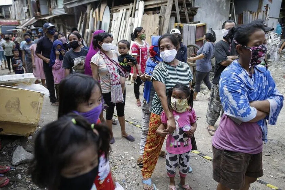 Penduduk setinggan di Jakarta memakai pelitup ketika beratur untuk mendapatkan makanan tengah hari percuma pada Rabu (22 April).