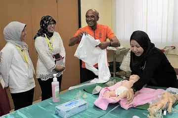 KERJASAMA: Dua peserta Indonesia (berbaju putih) terlibat dengan pasukan Relawan Antarabangsa Singapura (SIV) semasa demonstrasi di bengkel latihan. Projek ini bertujuan untuk membina keupayaan pekerja penjagaan kesihatan setempat untuk memberikan rawatan kritikal kepada bayi dan kanak-kanak yang berisiko. - Foto SIV