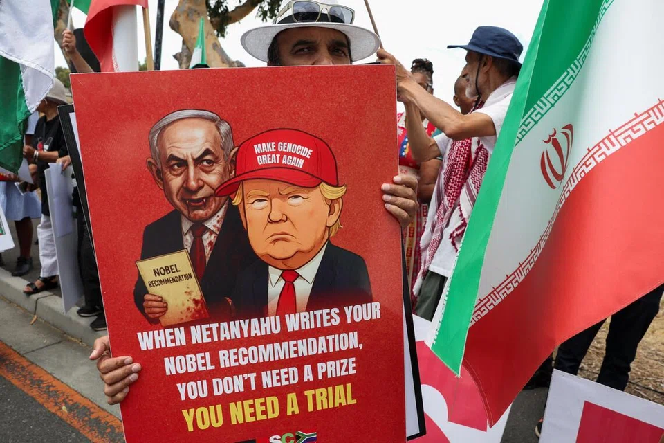 Seorang penunjuk perasaan memegang poster yang memaparkan Presiden Amerika Syarikat Donald Trump dan Perdana Menteri Israel Benjamin Netanyahu semasa protes solidariti di luar Kedutaan Amerika Syarikat bagi menyokong rakyat Venezuela, Iran dan Palestin di Cape Town, Afrika Selatan, pada 22 Januari 2026.