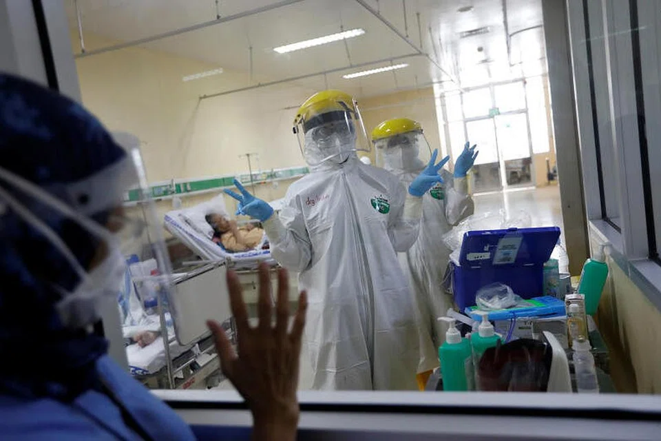 RAWAT PESAKIT: Petugas perubatan memakai pakaian pelindung diri memberi isyarat di bilik pengasingan bagi pesakit koronavirus selepas menjalankan ujian pengambilan swab, di unit kecemasan Hospital Persahabatan di Jakarta, Indonesia, semalam. 