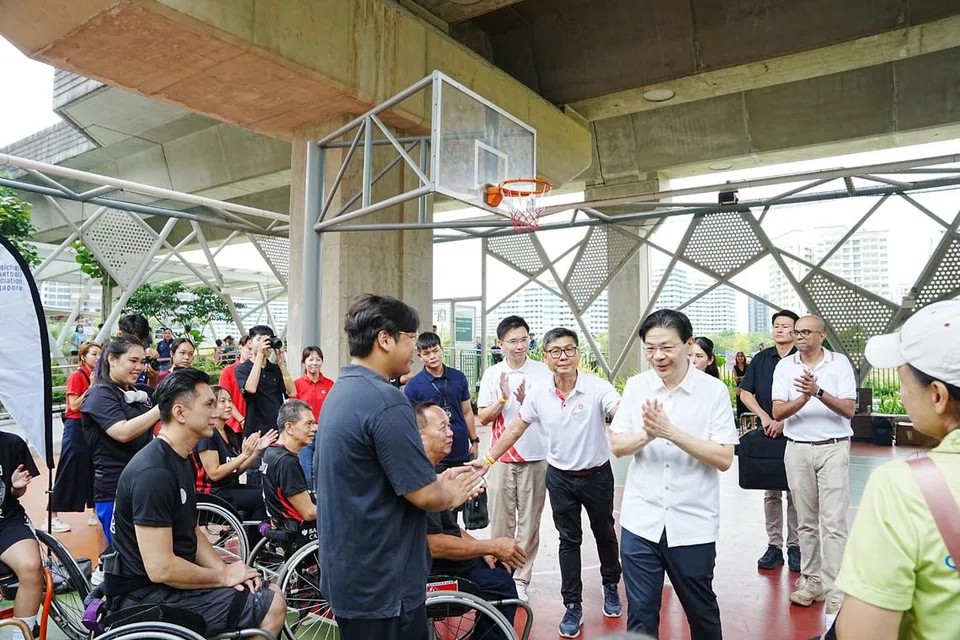 Perdana Menteri, Encik Lawrence Wong (berkemeja putih), bertemu dengan pemain bola keranjang berkerusi roda di Punggol Green, laluan berjalan kaki berteduh yang menghubungkan One Punggol dengan pusat beli-belah Waterway Point.