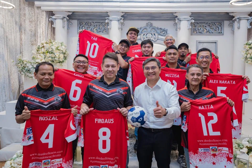 BANGGA SARUNG JERSI: Encik Hatta (depan, kanan, jersi nombor 12) bangga dapat mewakili Singapura bersama rakan-rakan sepasukannya ke Piala Negara Sedunia Bola Sepak Berjalan di England yang turut mendapat sokongan Encik Saktiandi (depan, dua dari kanan).