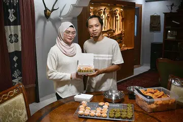 BEKERJASAMA: Cik Nursyazwani Ridzwan dan Encik Abdul Walid Mohamed Moehtar mengambil masa setengah hari, dari subuh hingga zuhur untuk membuat kuih keria. Dengan tenaga yang digabungkan, pasangan itu boleh mencapai 500 keping kuih keria dalam masa yang ditentukan. - Foto BM oleh ARIFFIN JAMAR