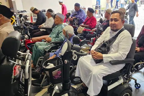 Encik Mas Imran, 43 tahun (depan, kanan), yang terpaksa menggunakan 
Alat Bantuan Mobiliti Peribadi (PMA), merupakan antara anggota jemaah yang meraih manfaat daripada ruang ‘drive-thru’ yang disediakan oleh Masjid Darul Makmur.
