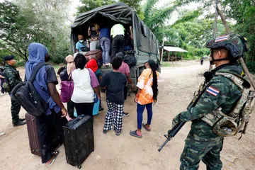 Orang ramai dari pelbagai negara yang bekerja di kompleks KK Park di Myanmar menaiki kenderaan selepas menyeberangi Sungai Moei ke Thailand, sementara askar Thai mengawal kawasan di Daerah Mae Sot, Wilayah Tak pada 24 Oktober 2025. Lebih daripada 1,000 orang dilaporkan melarikan diri dari Myanmar ke Thailand minggu ini selepas tentera Myanmar menyerbu salah satu pusat penipuan terbesar di negara itu.