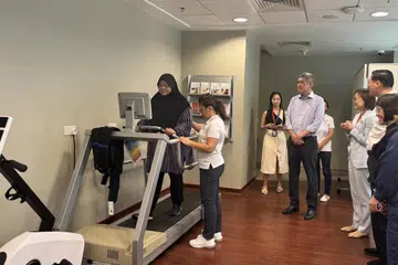 Pesakit barah buah dada, Cik Rozita Abidinsah (kiri), menunjukkan contoh latihan pemulihan di majlis pembukaan Pusat Pemulihan Persatuan Barah Singapura (SCS) di Institut Barah Universiti Nasional Singapura (NCIS) pada 12 September. Antara yang hadir ialah Pengerusi SCS, Encik Lee Meng Tat (empat dari kanan).