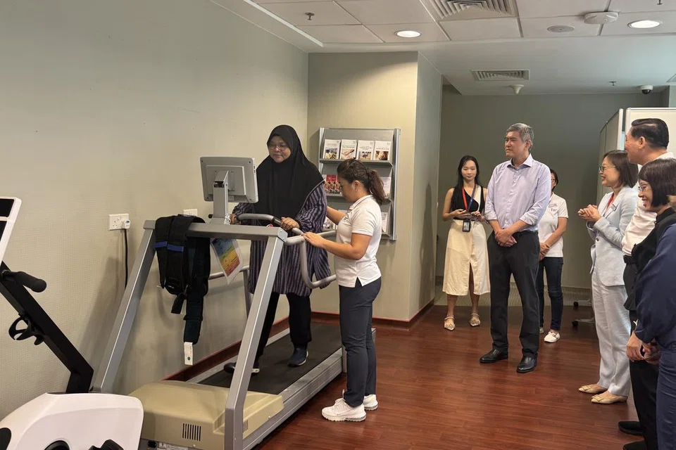 Pesakit barah buah dada, Cik Rozita Abidinsah (kiri), menunjukkan contoh latihan pemulihan di majlis pembukaan Pusat Pemulihan Persatuan Barah Singapura (SCS) di Institut Barah Universiti Nasional Singapura (NCIS) pada 12 September. Antara yang hadir ialah Pengerusi SCS, Encik Lee Meng Tat (empat dari kanan).