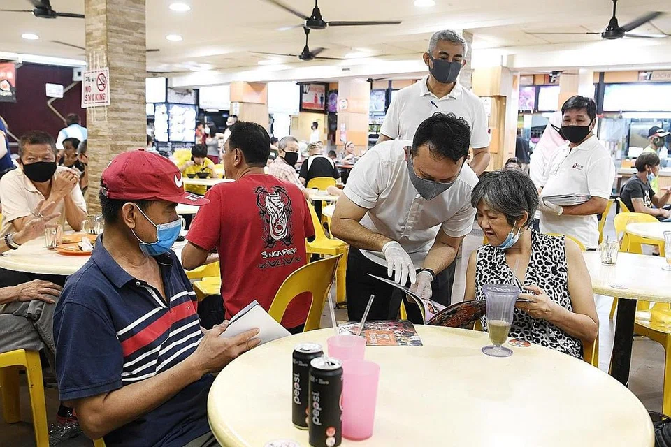 BERI PENERANGAN: Encik Zaqy (membongkok) memberi penerangan kepada seorang penduduk di sebuah kedai kopi semasa satu lawatan mendekati penduduk di Blok 131 Marsiling Rise malam kelmarin. - Foto BM oleh KHALID BABA