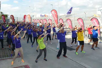 GAYA HIDUP SIHAT: Menteri Kebudayaan, Masyarakat dan Belia, Cik Grace Fu (baris depan, kiri), bersama kakitangan FedEx Express melakukan senaman di premis syarikat tersebut. - Foto THE STRAITS TIMES