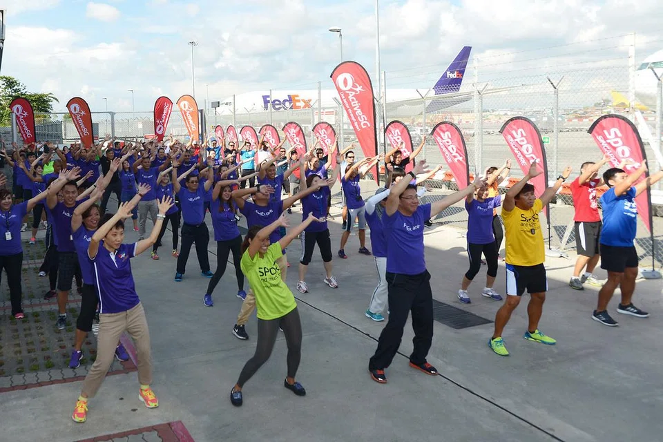 GAYA HIDUP SIHAT: Menteri Kebudayaan, Masyarakat dan Belia, Cik Grace Fu (baris depan, kiri), bersama kakitangan FedEx Express melakukan senaman di premis syarikat tersebut. - Foto THE STRAITS TIMES