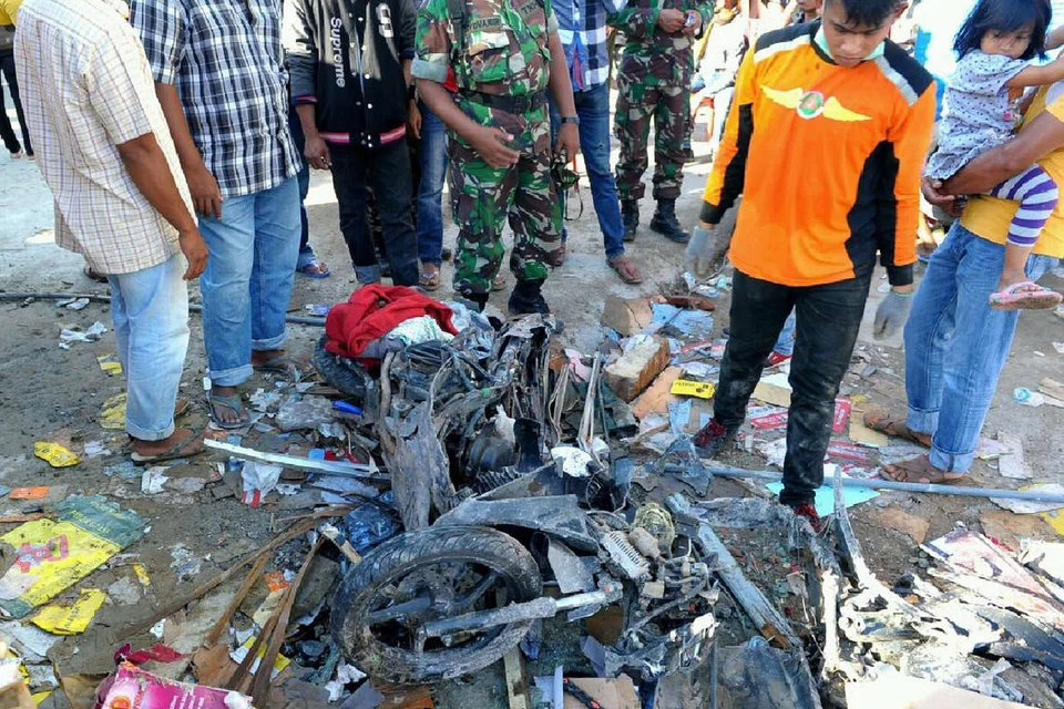 TURUT ROSAK: Penduduk Aceh berdiri di sebelah motosikal yang rosak teruk akibat gempa di Aceh kelmarin
