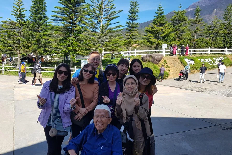 Cik Norilah Suja’i (kanan bertudung), berserta suaminya, Ustaz Sallim Jasman (depan, kopiah putih), bermesra dengan sekumpulan warga Singapura lain di Desa Dairy Farm dengan berlatar belakang Gunung Kinabalu.