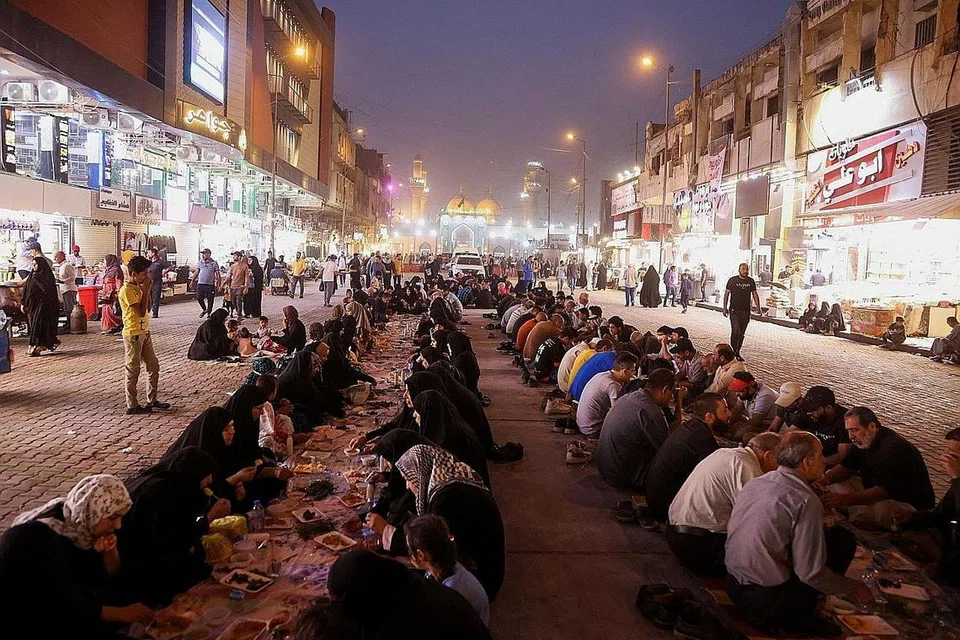 BERBUKA BERSAMA: Umat Islam Iraq sedang berbuka puasa dengan duduk di satu jalanan di daerah Kadhimiya, ibu kota Baghdad, Iraq.- Foto REUTERS 