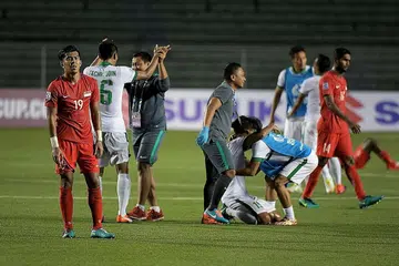 WAJAH HAMPA: Dua tunggak Singa, kapten Hariss Harun (kanan) dan Khairul Amri (jersi 19), kecewa di akhir perlawanan sedang para pemain Indonesia (berjersi putih) meraikan kejayaan melayakkan diri ke separuh akhir. - Foto THE STRAITS TIMES