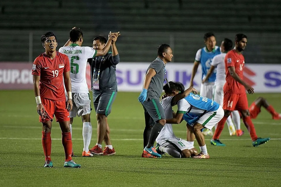 WAJAH HAMPA: Dua tunggak Singa, kapten Hariss Harun (kanan) dan Khairul Amri (jersi 19), kecewa di akhir perlawanan sedang para pemain Indonesia (berjersi putih) meraikan kejayaan melayakkan diri ke separuh akhir. - Foto THE STRAITS TIMES