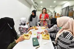 SUASANA KEKELUARGAAN TERASA: Pembantu rumah di rumah perlindungan Home yang dirujuk ke situ menyusuli aduan didera atau disalah guna majikan berpeluang menikmati ukhuwah pihak pengurusan seperti anggota Lembaga Pengarah Home, Cik Linda Ma'arof (berdiri di kiri) dan Pemangku Pengarah Eksekutif Home, Cik Deshi Gill (berdiri, kanan). - Foto BM oleh DESMOND WEE