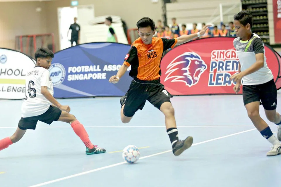 GAGAL DIBENDUNG: Pemain dari Sekolah Menengah Marsiling (tengah) berjaya mengelak dari cabaran pemain Sekolah Menengah Mayflower dalam perlawanan Kumpulan B semalam. Marsiling berjaya menduduki tangga pertama selepas tiga perlawanan dan berjaya melangkah ke peringkat seterusnya. - Foto FAS