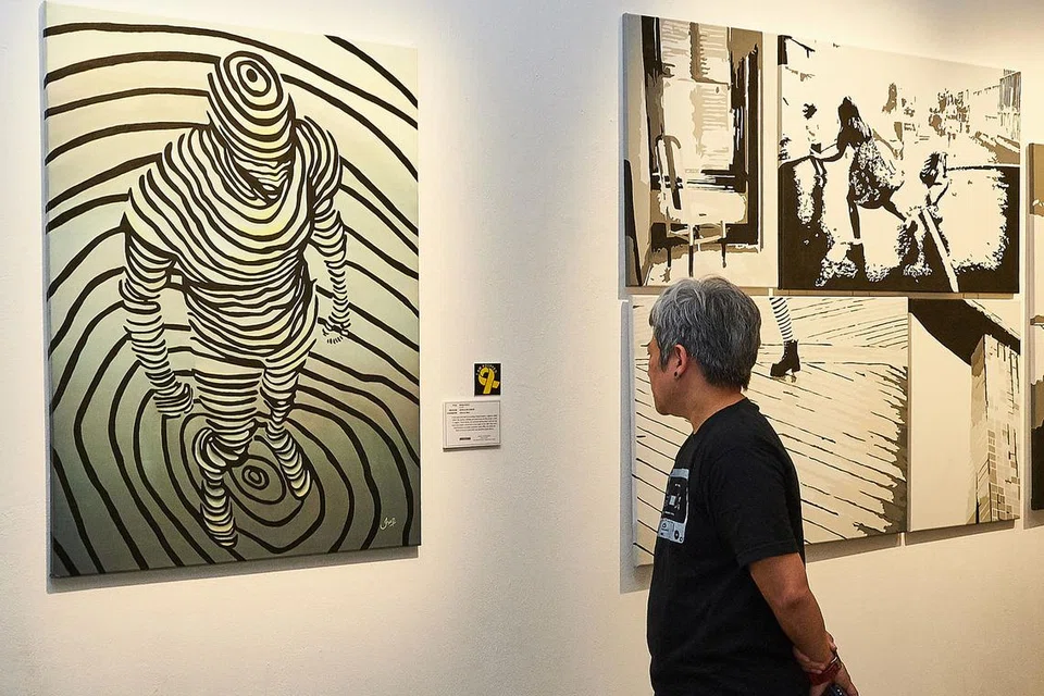 PERHATIKAN LUKISAN: Seorang pengunjung ke Pameran Seni dan Puisi Masyarakat Reben Kuning (YRCAPE) melihat lukisan yang dihasilkan seorang banduan yang dipamerkan di Sota. - Foto BH oleh ROSLEE ABDUL RAZAK