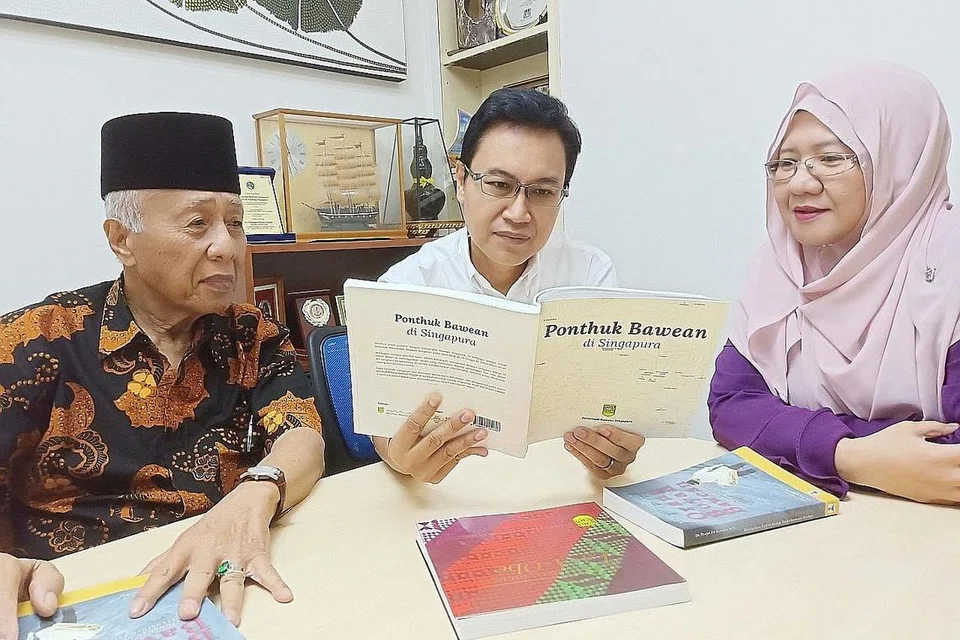 JERIH PERIH JEJAK BEKAS PENGHUNI PONDOK BAWEAN BERBALOI: Tiga orang kuat Persatuan Bawean Singapura - presiden Encik Faizal Wahyuni (tengah), penasihat Encik Mohd Seain Matsom dan penolong setiausaha Cik Nurul Sa'adah Mohd Seain - meneliti buku 'Ponthuk Bawean di Singapura'. - Foto BH oleh SAINI SALLEH