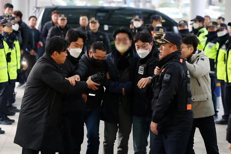 DITAHAN: Seorang lelaki (tengah, dengan muka kabur) dibawa pergi oleh polis di Busan, Korea Selatan, pada 2 Januari 2023, selepas berlaku insiden menikam ketua pembangkang Parti Demokratik.