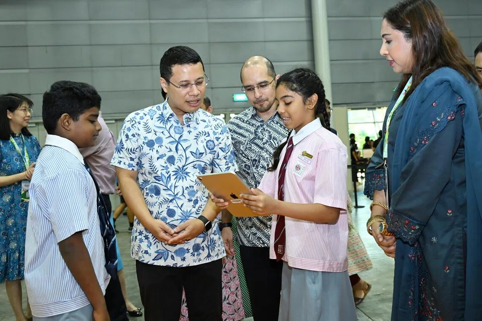 SIMPOSIUM BAHASA IBUNDA: Menteri Pendidikan, Encik Desmond Lee (dua dari kiri), dan Setiausaha Parlimen Kanan (Pendidikan merangkap Pembangunan Negara), Dr Syed Harun Alhabsyi (tengah), mencuba kegiatan di Simposium Bahasa Ibunda (MTLS) ke-14 di Singapore Expo pada 1 Ogos.