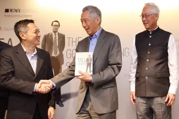 AUTOBIOGRAFI DILANCAR: Penulis buku 'Tall Order: The Goh Chok Tong Story', Encik Peh Shing Huei (kiri) menyerahkan senaskhah autobiografi itu kepada Perdana Menteri Lee Hsien Long dalam satu majlis pelancaran pada Khamis lalu, dengan disaksikan ESM Goh. - Foto BH oleh GAVIN FOO 