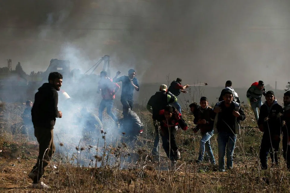 Warga Palestin yang sedang membantah di sempadan dengan Israel di Timur Gaza cuba melarikan diri dari bom gas pemedih mata yang ditembak oleh tentera Israel pada 8 Disember. 