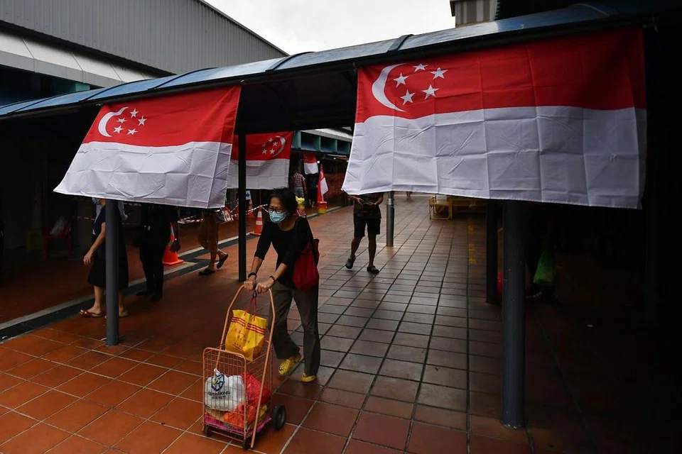 KIAN MENINGKAT: Penduduk dilihat memakai pelitup di Marsiling Lane Market sementara bendera Singapura dipasang di situ juga. - FOTO: LIM YAOHUI