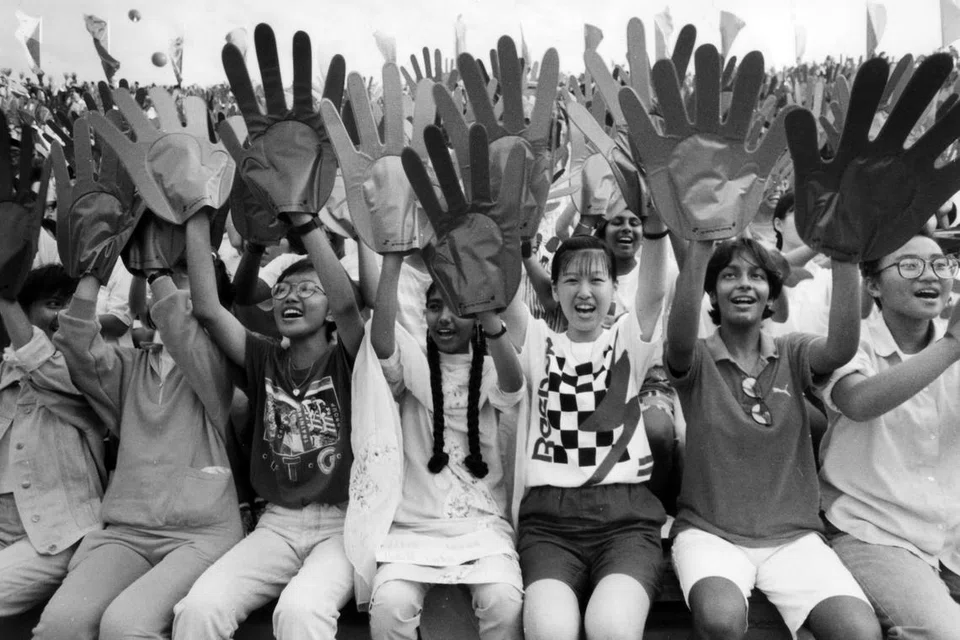 Bersorak sambil melambai untuk Singapura, para penonton yang dilengkapi dengan 60,000 pasang tangan mencipta gelombang berwarna jingga dan hijau pada 9 Ogos 1989.