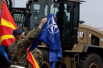 Seorang askar Macedonia Utara membetulkan bendera Nato semasa satu acara di Skopje, Macedonia Utara.
