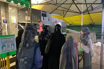 IMBAS SEBELUM MASUK: Seorang sukarelawan membantu dalam imbasan TraceTogether ke atas jemaah yang berpusu-pusu untuk masuk ke ruang solat Masjid Ar-Raudhah, baru-baru ini. - Foto MASJID AR-RAUDHAH