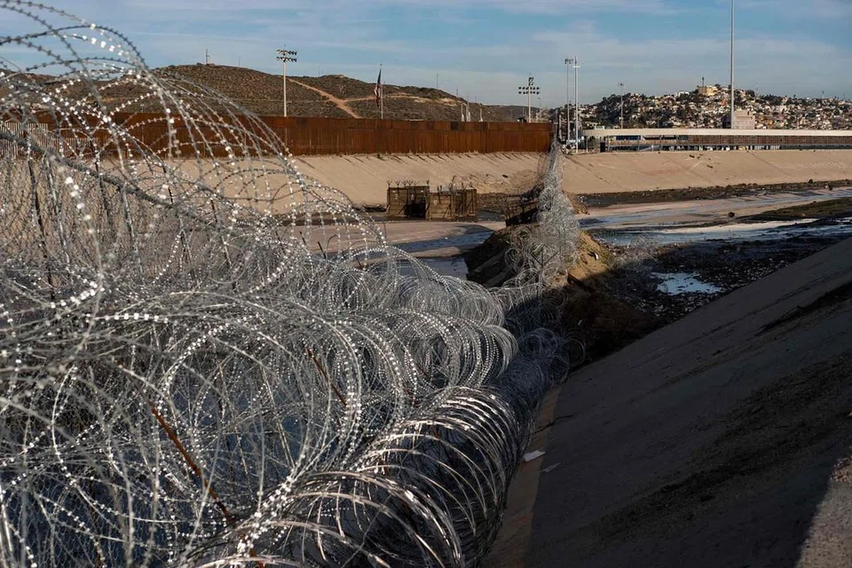 PUNCA ISU: Pagar dawai di sempadan Amerika-Mexico di Sungai Tijuana di negeri Baja California. Presiden Trump mahu membina tembok konkrit bagi menghalang pendatang haram, seperti rakyat Hondura ini, yang memanjat pagar di sempadan itu pada 6 Januari lalu ini untuk memasuki Amerika. - Foto AFP