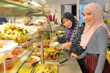 TEBAR SAYAP: Cik Mastura (kanan) berkata langkah membuka tujuh gerai 'mini' di serata Singapura itu bertujuan memastikan pelanggan tidak perlu ke dua restoran Hajah Maimunah - di Jalan Pisang dan Joo Chiat - untuk mendapatkan makanan kegemaran mereka. Gambar menunjukkan Cik Mastura dan ibunya, Cik Mahiran Abdul Rahman, di cawangan sedia ada.- Foto BM oleh KHALID BABA