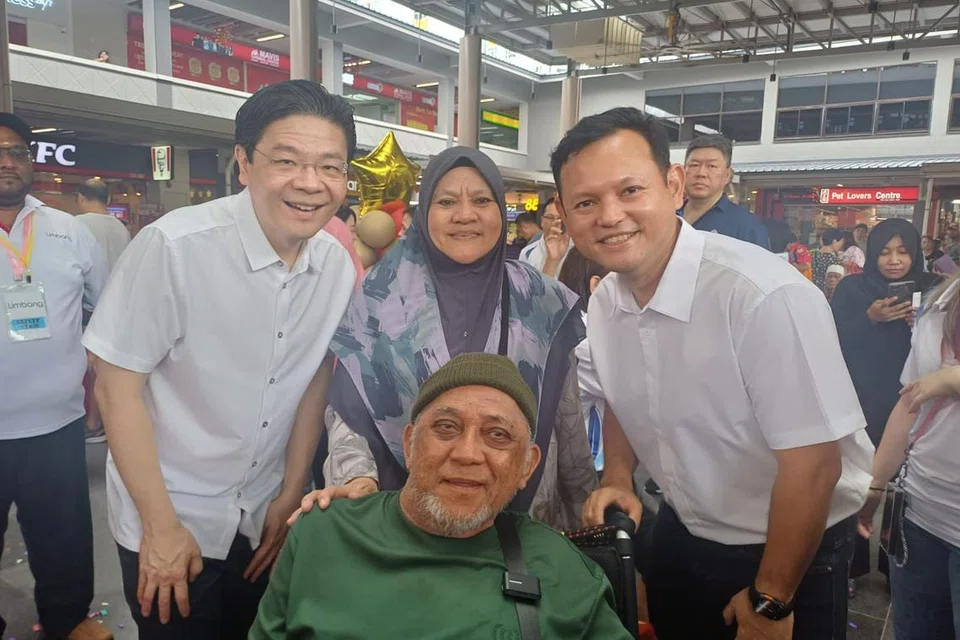 Encik Yusuf Saibi (berkerusi roda) bergambar bersama Perdana Menteri Encik Lawrence Wong (paling kiri) dan penasihat Pertubuhan Akar Umbi (GRO) GRC Marsiling-Yew Tee Encik Zaqy Mohamad di majlis pelancaran ‘Tawaran MY $1’. Turut bersamanya ialah isteri, Cik Endon Daromi (berdiri tengah). 