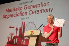 GENERASI MERDEKA: Encik Lee menunjukkan folder Generasi Merdeka yang diberikan kepada 8,300 warga Singapura menerusi pelbagai acara kemasyarakatan di seluruh negara hari ini.